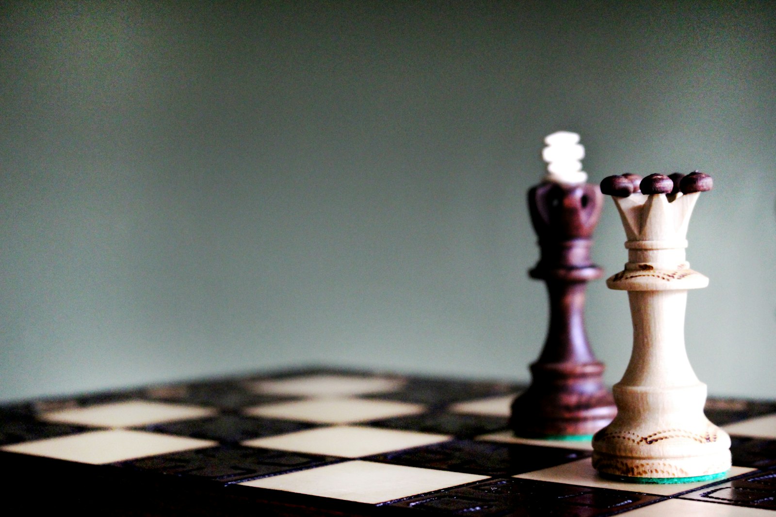 Queen and king chess pieces facing each other on a chessboard