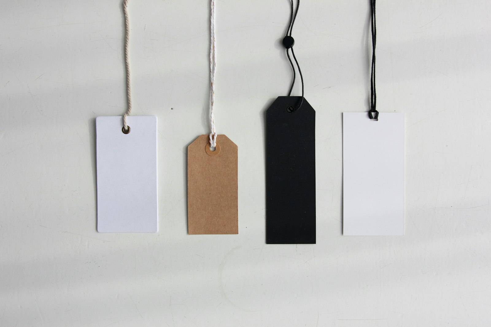 Four blank paper price tags on a neutral background